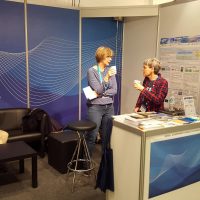 Two people with coffee standing at an information both in a conference center