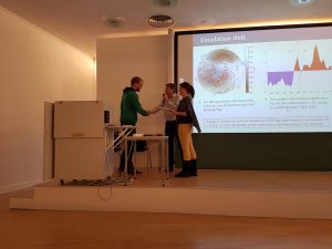 Three people on a stage in front of a presentation