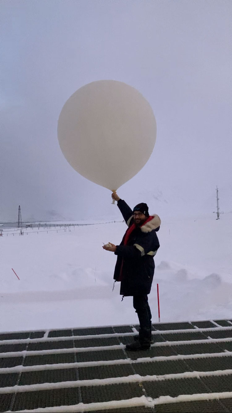 A scientist in a winter coat starting a weather balloon.