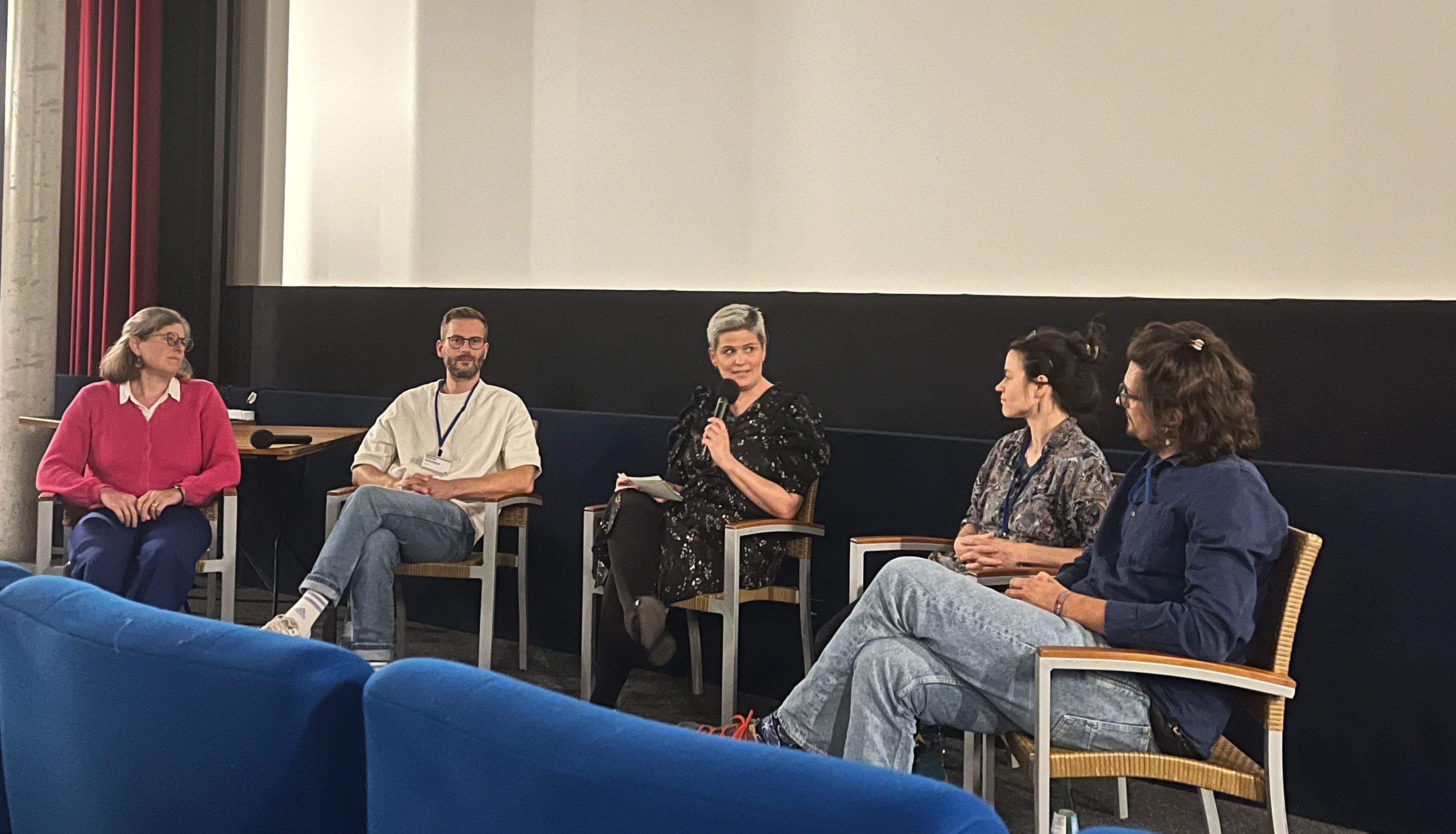 4 ac3 members together with a moderator infront of a cinema screen