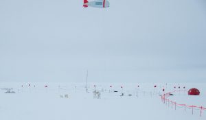 Wide angle shot of the TROPOS tethered balloon in the air with the guide flags up on the snow field