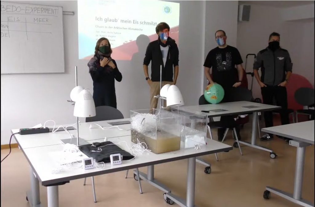 Four people in front of a class with experiments in the foreground