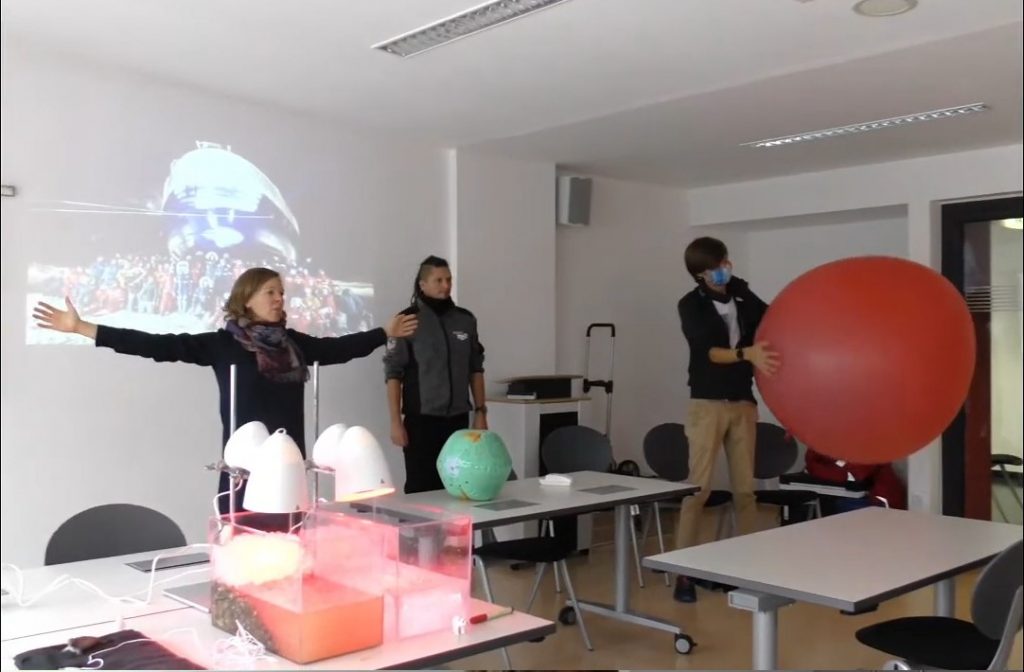 Three people on front of a class with experiments set up