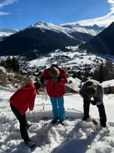 Three people on a snow pile in the mountains doing measurement